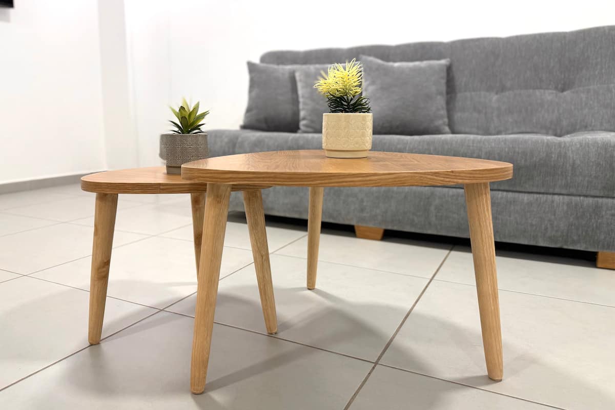 Mesas de centro de madera con materas frente al sofá gris de la sala