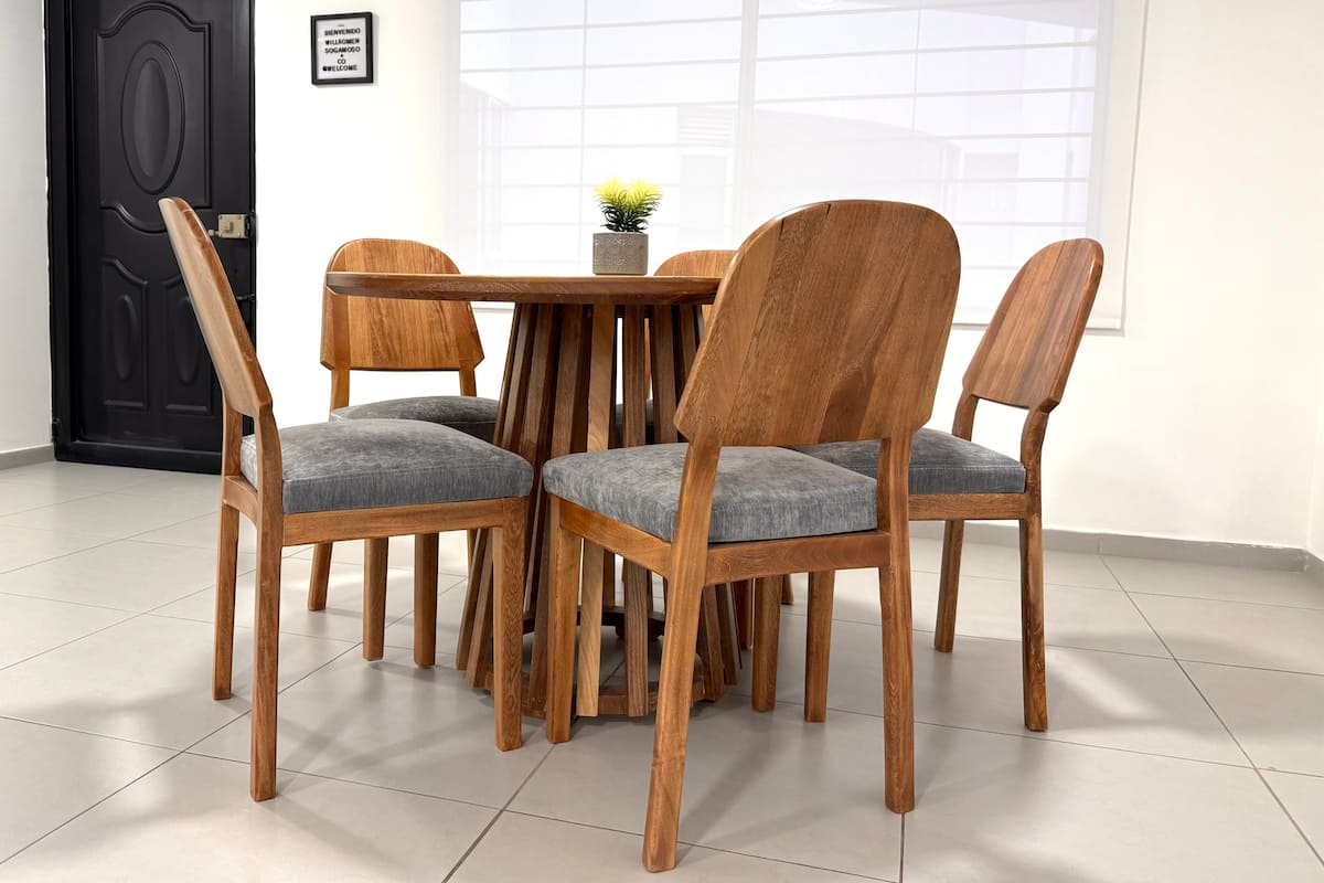 Comedor redondo de madera con cuatro sillas junto a la ventana y la puerta de entrada