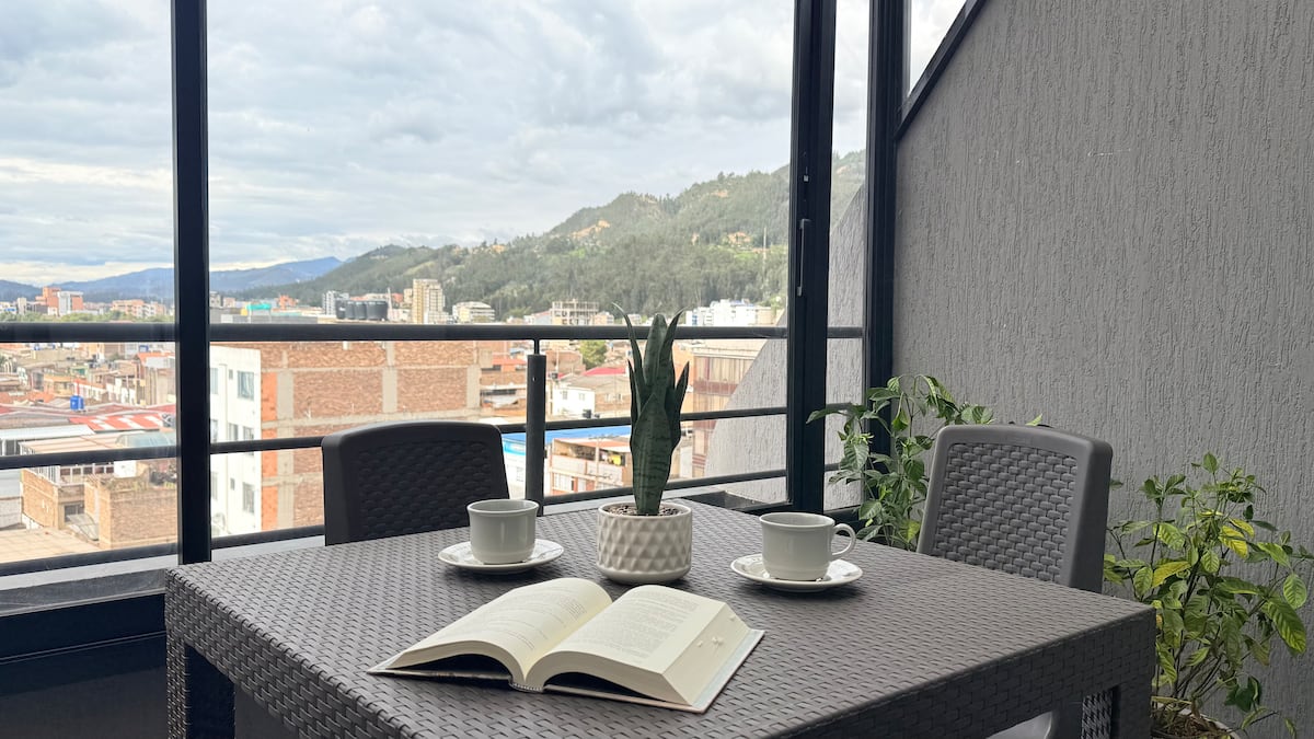 Mesa de la terraza con dos tazas y un libro abierto frente a la vista de la ciudad